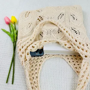 Nahaufnahme Detail der beigen gestrickten Schultertasche mit hohlem Muster und feiner Textur.