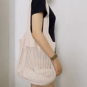 Detailaufnahme einer beigen gestrickten Schultertasche mit Lochmuster für den Alltag.