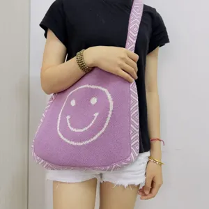 Gepflegte Damen Umhängetasche aus Strick in Lila mit einem niedlichen weißen Smiley Gesicht.