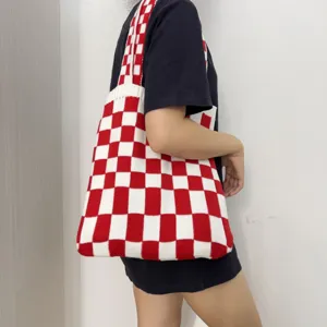 Detailansicht einer rot-weiß karierten Strick-Schultertasche, elegant vom Model getragen.