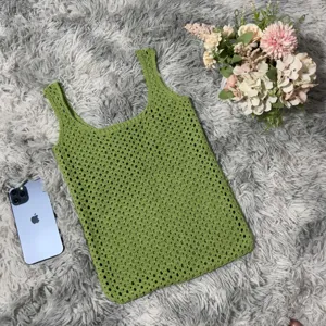 Grüne gehäkelte Lochstrick Tasche Detailaufnahme auf flauschigem Teppich mit Blumendekor
