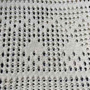 Nahaufnahme des Strickstoff Textur Details in hellem Cremeweiss mit Lochmuster Design.