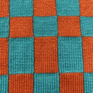 Detailaufnahme der trendigen orange-türkisen Karo-Strickstoff-Textur des Beutels.