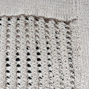 Nahaufnahme von beigeem Strick-Netzstoff mit detailliertem hohlem Design für Tasche.