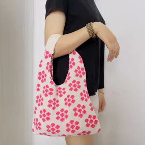 Nahaufnahme der Strick-Umhängetasche mit rosa Blumenmuster, bequeme Textur für den Alltag.