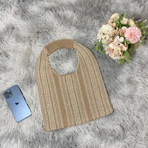 Detailed shot of casual knit shoulder bag with vertical geometric stripes and cozy fur background.