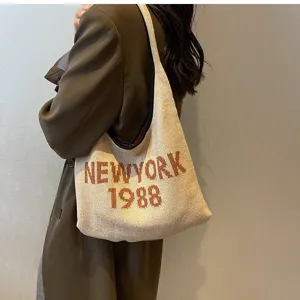 Detailansicht einer beige Strick-Umhängetasche mit retro New York Buchstaben-Strickdesign, lässig.