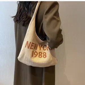 Strick-Umhängetasche Detail mit Vintage New York 1988 Textmuster und weicher Stofftextur.