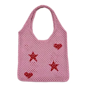 Nahaufnahme der rosa Strick-Tragetasche mit gewebten roten Herz- und Sternmustern.
