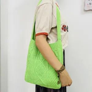 Detailansicht einer hellgrünen Strick-Schultertasche mit klassischem Zopfmuster getragen.