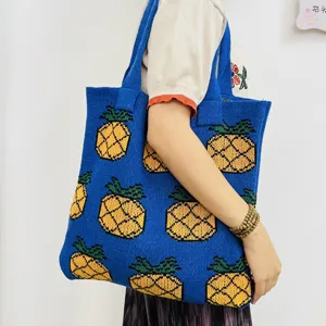 Close-up detail of the blue knitted tote bag featuring a cute yellow pineapple pattern.