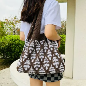 Gestrickte Schultertasche mit braunem und weißem Rautenmuster und lässigem Lochdesign.