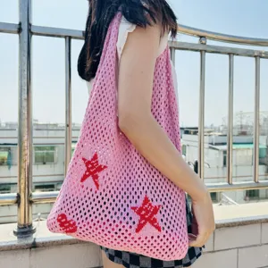 Rosa Strick Netz Tasche Detail Ansicht mit Schultergurt und rotem Sternen Muster Design.