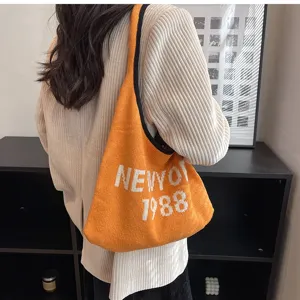 Detailaufnahme einer orangefarbenen Strick-Umhängetasche mit gewebtem Text und hochwertiger Optik.