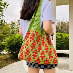 Detaillierte Ansicht des grünen Strick-Tote-Bags mit rotem Muster bei Outdoor-Nutzung.