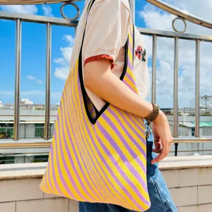 Primo piano dettaglio di una borsa tote in maglia a righe gialle e viola a spalla.