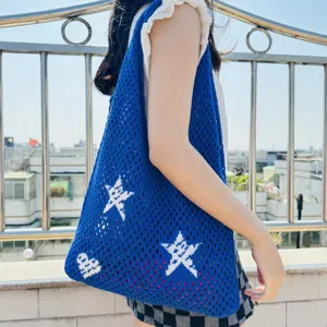 Blau gestrickte Häkel Tragetasche Detailaufnahme mit Lochmuster und weißen Sternen an Schulter.