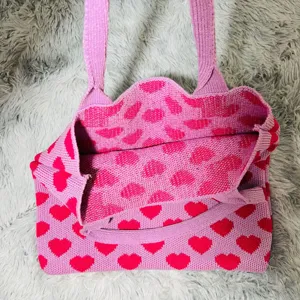 Detailaufnahme der rosa Strick-Tasche mit rotem Herz-Muster, weiches Material und modischer Look.