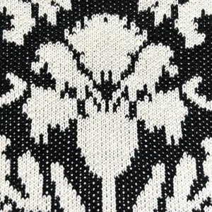 Nahaufnahme der schwarz-weißen Strickstoff-Textur mit Blumenmuster-Detail für Tasche.