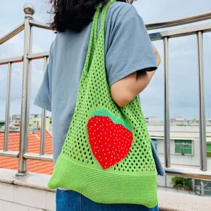 Grüne gestrickte Netz-Tragetasche mit süßem rotem Erdbeermuster für den täglichen Gebrauch.