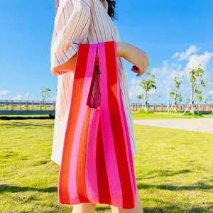Detailaufnahme einer bunten gestreiften Stricktasche im Freien, stilvolles modisches Accessoire.
