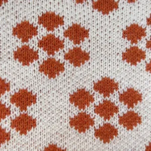 Nahaufnahme von Strickstoff, weiche Textur mit orangefarbenen Punkten für Taschen und Kleidung.