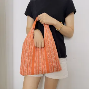 Orange knitted shoulder tote bag with geometric pattern, casual fashion underarm handbag.