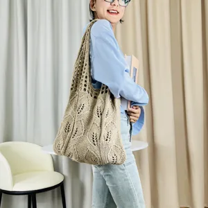Detailansicht der beigen, gehäkelten Schultertasche mit filigranem Blattmuster beim Tragen.