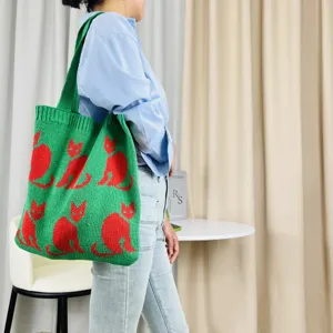 Detailansicht der grünen Strick-Toten Tasche mit rotem Katzenmuster, am Model präsentiert.