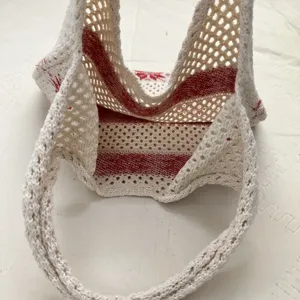 Strick-Häkel-Tragetasche Detail mit dem ausgehöhlten rot-weißen Streifenmuster.