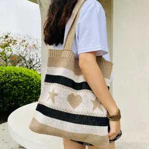 Detailansicht der gestrickten Tasche mit stilvollen Streifen, Sternen und Herzen.