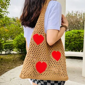 Detailansicht der braunen Häkel-Tasche mit roten Herzmustern und luftigem Strick-Netzdesign.