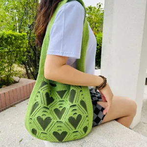 Bolso tote de hombro tejido en verde con un elegante detalle de patrón de corazón.
