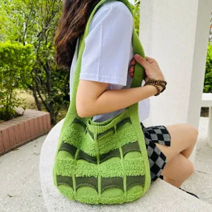Detaillierte Ansicht einer stilvollen grünen gestrickten Schultertasche im Freien.