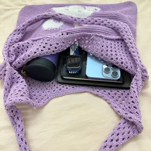 Detailansicht einer lila Strick-Totetasche mit geräumigem Innenraum und Alltagsgegenständen.