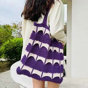 Detailansicht einer violett-weißen Strick-Tasche über der Schulter, stilvolles Gewebe-Design.