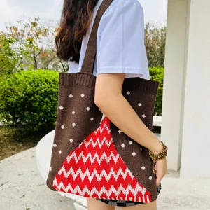 Detailaufnahme einer Strick-Tasche mit braunem Schneeflocken-Muster und rot-weißem Weihnachtsbaum.