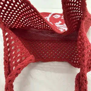 Rote gestrickte hohle Tragetasche Detailansicht zeigt erstklassige Web-Netz-Handwerkskunst.