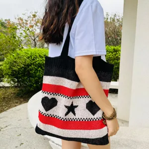 Detailansicht der Strick-Tasche mit schwarz-weiß-rot gestreiften Herz- und Sternmotiven.