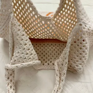 Nahaufnahme der beigen gestrickten Beuteltasche mit Netzgewebe und Strukturdetails.