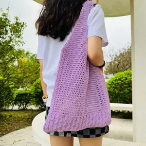 Detailaufnahme einer stylischen hellvioletten Strick-Hohl-Umhängetasche draußen.