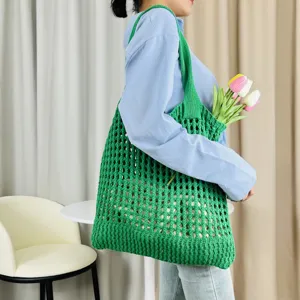 Grüne gestrickte hohle Umhängetasche Detailansicht mit Blumendekoration in Szenenpräsentation.