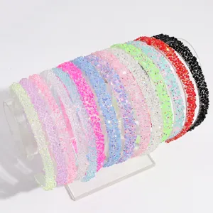Detailed view of multiple colorful rhinestone thin hair hoops set on a clear stand.