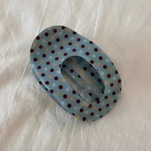 Elegante molletta per capelli ovale a pois blu, accessorio chic per acconciature moderne.