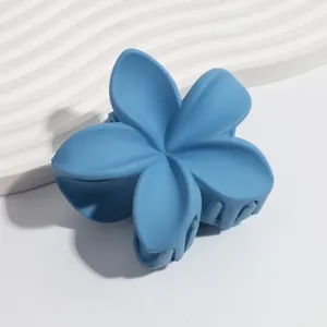 Close-up detail of a vibrant blue matte plumeria flower hair claw clip, elegant design.