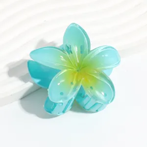 Close-up detail of the translucent blue and yellow plumeria flower hair claw clip.