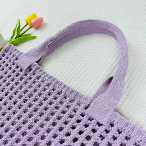 Nahaufnahme einer lila geflochtenen Schultertasche mit Lochmuster, elegant und schick.