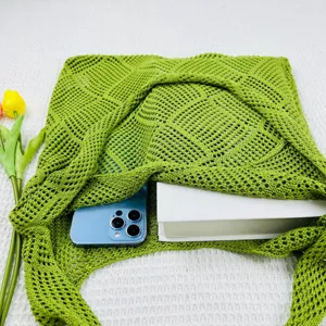 Grüne gestrickte hohle Netztasche Detailaufnahme zeigt geräumige Kapazität und Alltagsgegenstände.
