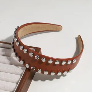Gros plan détaillé du serre-tête large en cuir PU marron avec clous métalliques argentés.