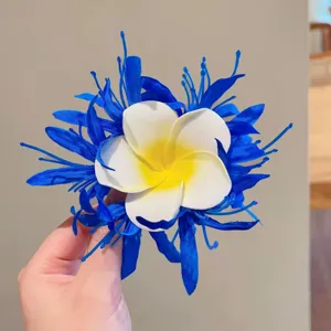 Detail of floral hair clip featuring white plumeria flower and blue petals for summer style.